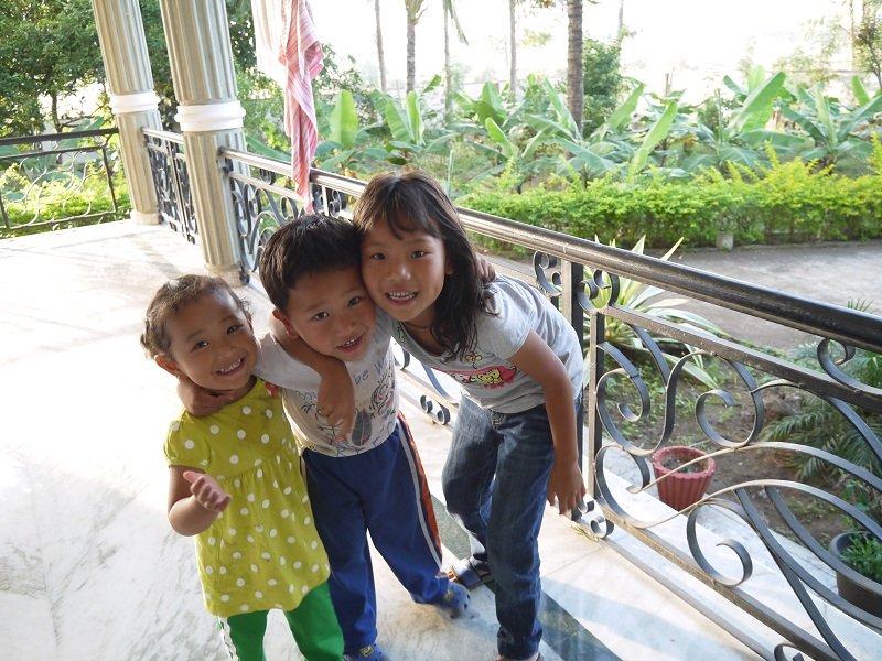 民宿老闆的一對可愛小寶寶（左一、二）在花園裏與鄰家女孩玩耍。後方可見自家種植的蕉樹和椰子樹。