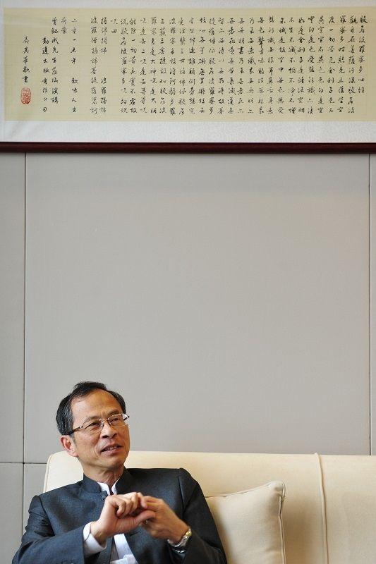 曾鈺成徐徐坐在一幅手書《心經》下，談論閱讀與傳統的力量。