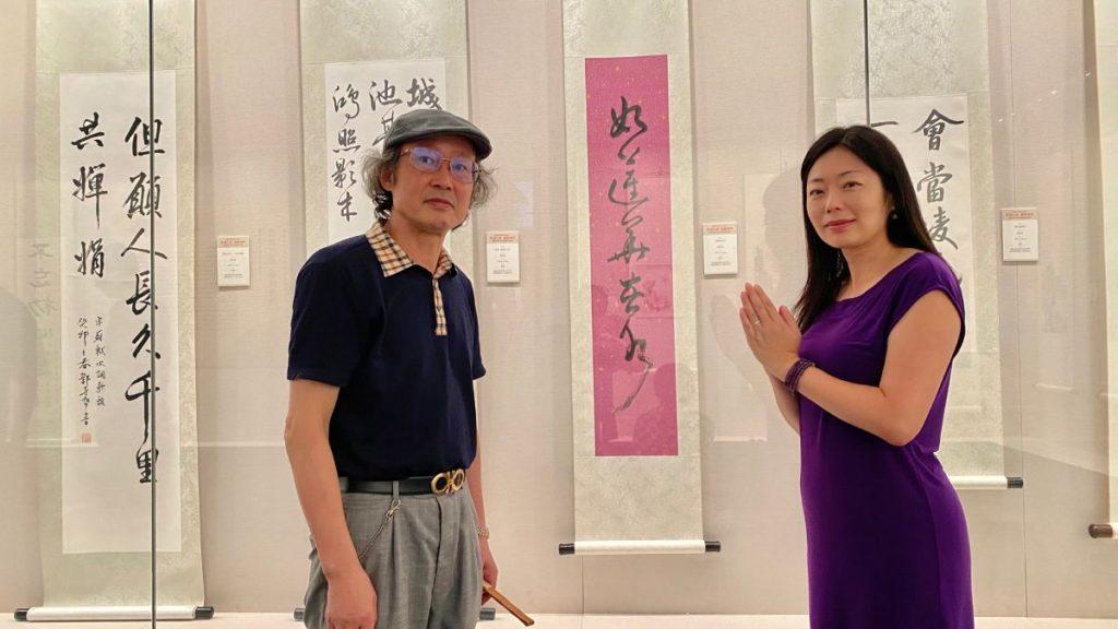 作者與白鶴教授於書法展覧作品「如蓮華在水」前合照。(作者提供)