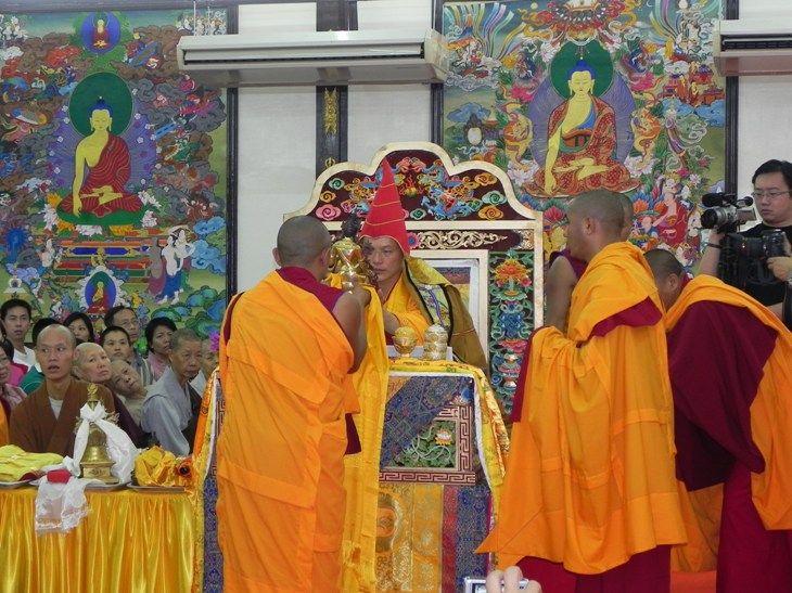 喇嘛為班諾仁波切(中坐者)穿上法衣並獻上吉祥物