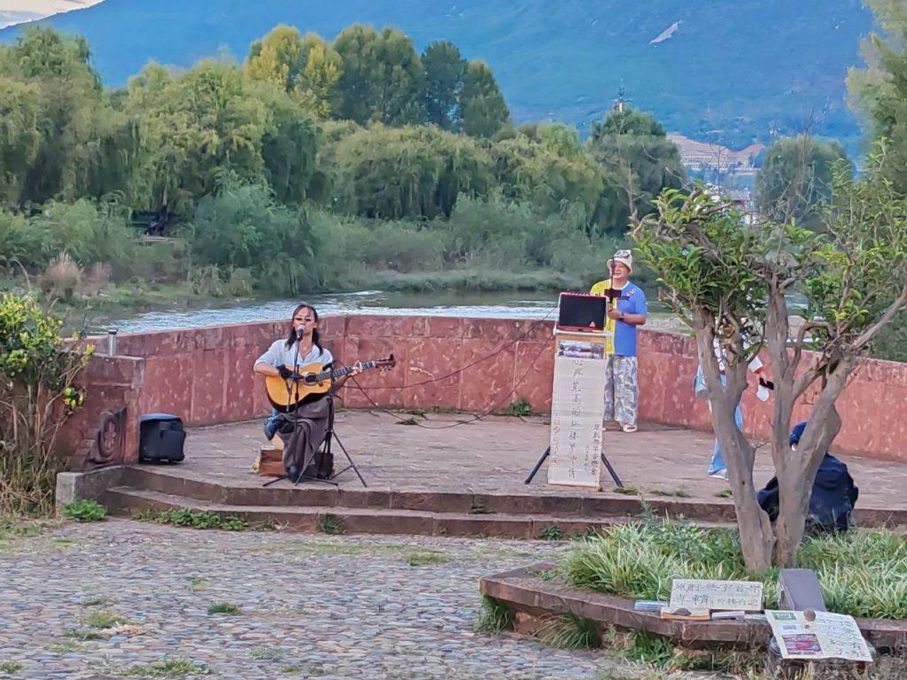 素人歌手在石墩上彈吉他、唱歌。