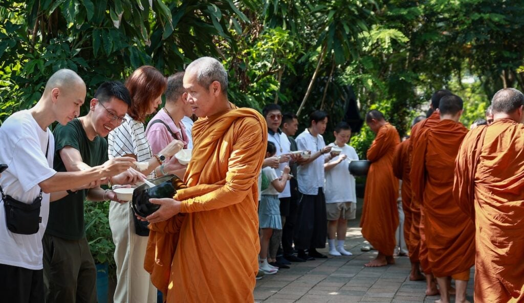 信眾們一早前往下白泥泰國寺恭敬供養僧寶。圖為龍婆與僧團一同接受信眾的虔誠供養。