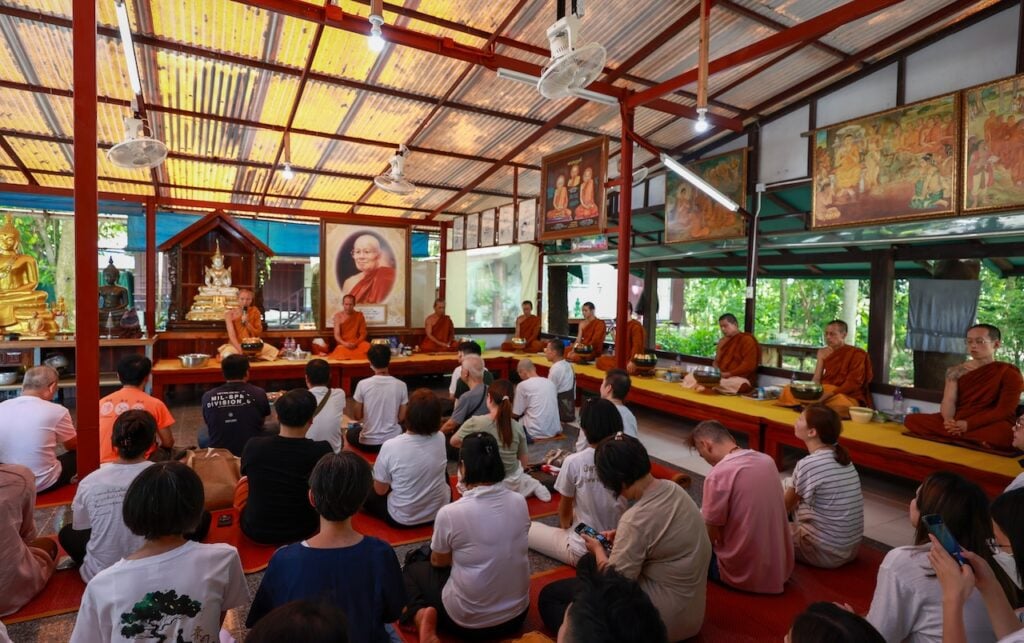 泰國寺的大殿僅是一座簡陋的鐵皮屋。眾人圍坐室內，體感溫度幾近 40°C，不少義工與信眾雖然都已汗流浹背，但不減他們聽聞佛法的虔誠心。